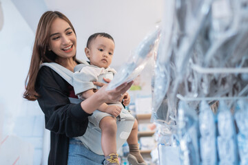 Wall Mural - asian mother with her toddler boy shopping in the baby shop