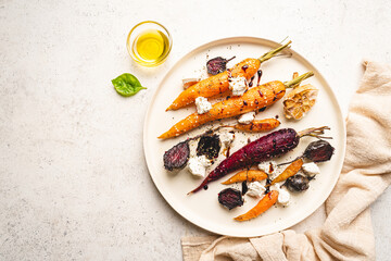 Wall Mural - Roasted young whole colorful carrot with herbs and cheese served on plate over white background. Top view