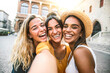 © Davide Angelini - Three young women taking selfie portrait on city street - Multicultural female friends having fun on vacation hanging outdoor - Friendship and happy lifestyle concept