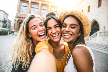 Three young women taking selfie portrait on city street - Multicultural female friends having fun on vacation hanging outdoor - Friendship and happy lifestyle concept