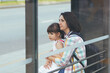 A young woman with her daughter is waiting for a public bus at the bus station