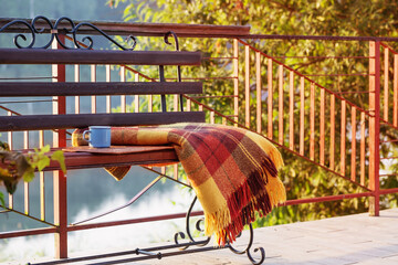 Wall Mural - cup of tea and warm plaid on wooden bench outdoor