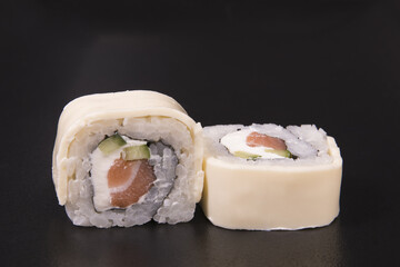 Wall Mural - Closeup of ouble salmon and cheese sushi rolls on a black background