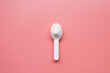 © Anton - White collagen powder on a plastic measure spoon on a pink background.
