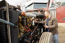 Male Mechanic Inspecting Semi Truck Engine