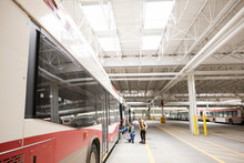 Engineers Inspecting Bus In Transit Garage