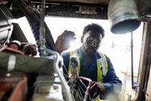 Male Mechanic With Flashlight Inspecting Engine