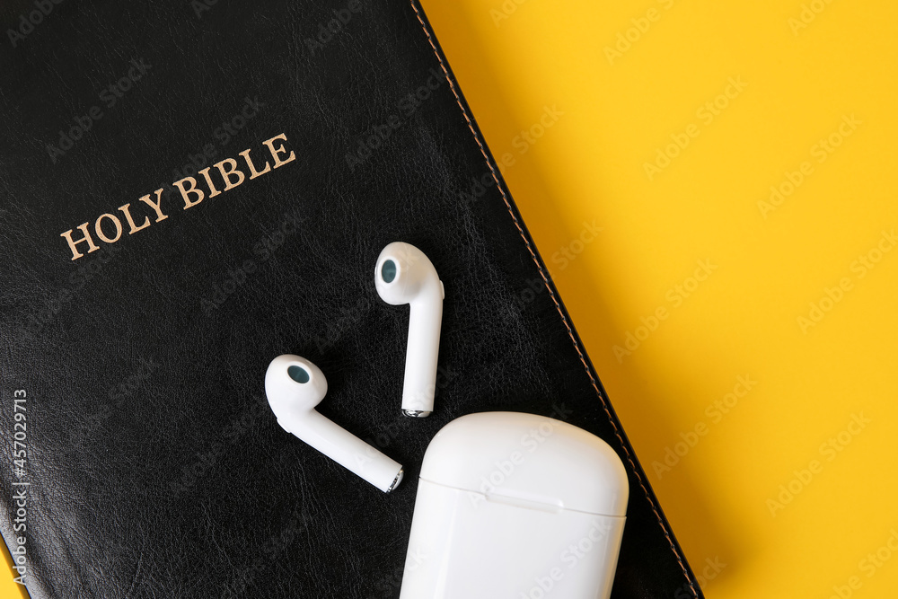 Holy Bible and earphones on color background, closeup