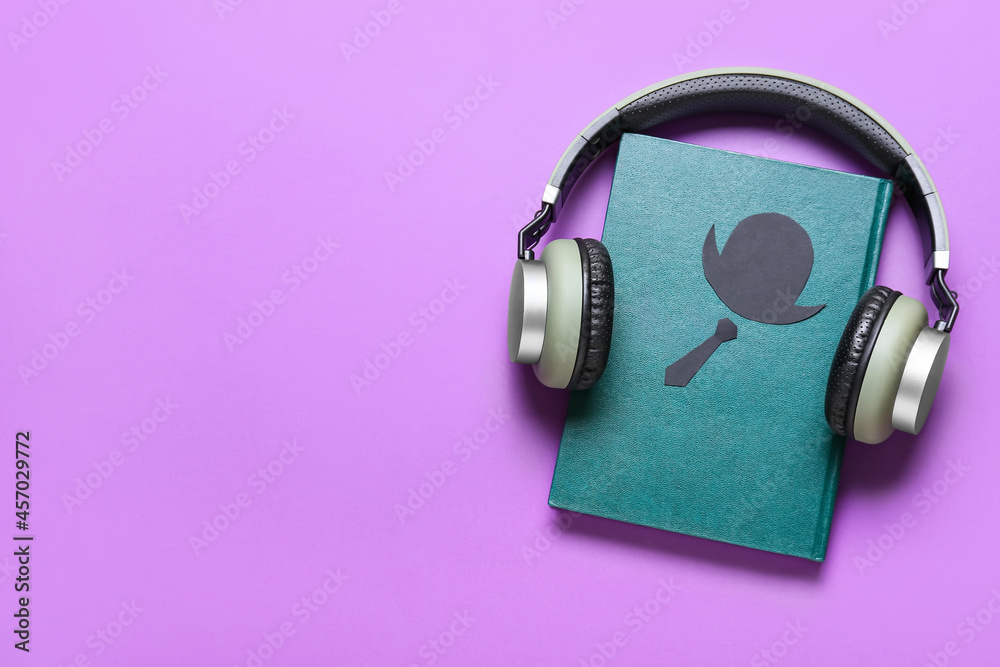 Modern headphones with book on color background