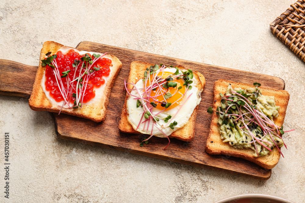 Wooden board with different toasts on grunge background