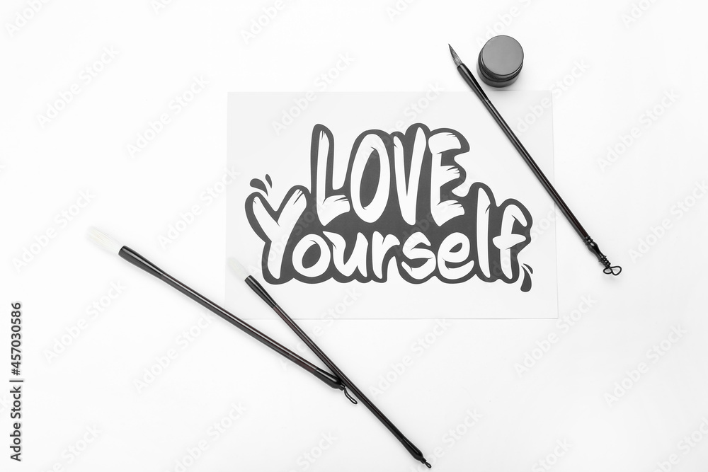 Paper with text LOVE YOURSELF and brushes on white background