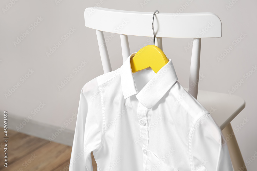 Chair with school shirt near light wall