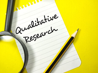 Business concept.Text Qualitative Research writing on notepaper with pencil and magnifying glass on yellow background.