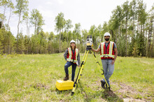 Portrait Of Surveyors Using Equipment To Measure Field