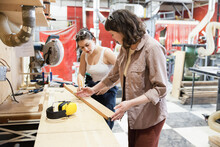 Female Woodworkers Preparing Wood In Workshop