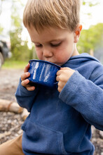 Portrait Of Boy Drinking Hot Chocolate In Front Of Caravan