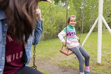 Mother Playing With Daughter On Swing