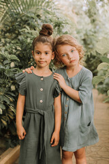 portrait of two charming smiling girls belonging to different races surrounded by tropical leaves. f