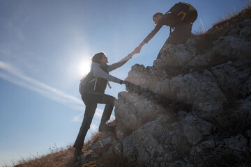 Help and assistance concept. Silhouettes of two people climbing mountains and helping against the blue sky. Walk in the clouds. Discovery Travel Direction Concept