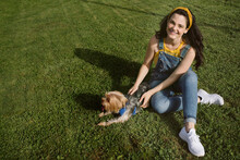 Smiling Woman Sitting On Grass With Purebred Puppy