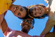 Multi ethnic group of friends looking at the camera and standing in circle, low angle view, happy people having fun