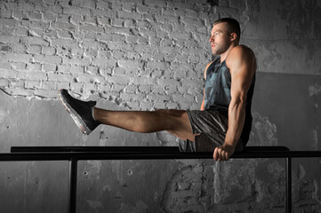 Poster - fitness, sport, bodybuilding and people concept - young man doing abdominal exercise on parallel bars in gym