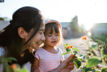 Mother and daughter picking pretty colourful flowes in the park