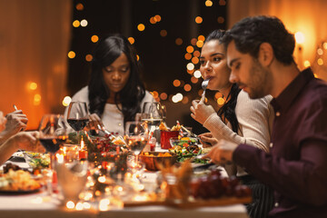 holidays, party and celebration concept - multiethnic group of happy friends having christmas dinner at home