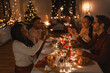 © Syda Productions - holidays and celebration concept - multiethnic group of happy friends with sparklers having christmas dinner at home