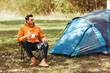 © Syda Productions - camping, tourism and travel concept - happy man drinking tea at tent camp