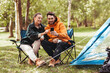 © Syda Productions - camping, tourism and travel concept - happy couple with smartphone drinking tea at campsite