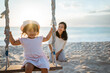 happy Little girl and mother swinging at the beach