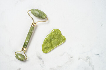 Fototapete - Jade roller and gua sha stone massager at white bath towel. Anti aging therapy. Top view with copy space..
