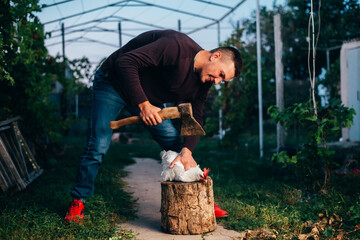 a man in clean clothes in the evening with an axe tries to kill a chicken