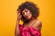 © Look! - close-up of charming African woman with bright makeup looks at camera while holding her hair with one hand. beauty in summer crimson dress with bare shoulders with lush short hair.