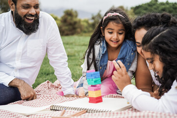 Wall Mural - indian parents having fun at city park playing together with wood toys at city park - focus on girl 