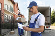 © New Africa - Moving service workers outdoors, unloading boxes and checking list