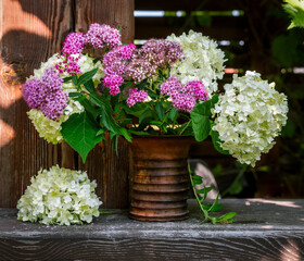 Wall Mural - Still life with a bouquet of white and lilac flowers in a ceramic vase. Blooming hydrangea. Vintage.