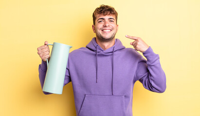 Wall Mural - young handsome man smiling confidently pointing to own broad smile. thermos concept