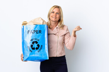 Wall Mural - Middle age woman holding a recycling bag full of paper to recycle isolated on white background pointing to the side to present a product