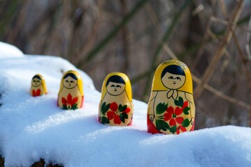 Wall Mural - Figurines of nesting dolls in the winter forest.