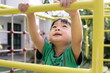 little asian boy climbs up the ladder on the playground