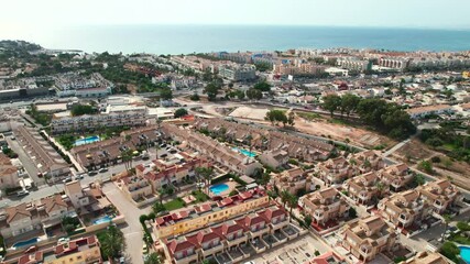 Wall Mural - Aerial drone point of view Cabo Roig townscape on the Costa Blanca of Spanish tourist resort, blue waters of Mediterranean Sea, modern residential neighbourhood. Summer holidays concept. Europe, Spain