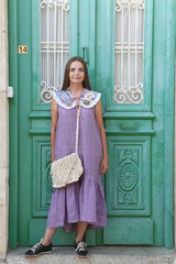 Wall Mural - Russian fashion woman and old door. Retro look with purple collar, violet dress. Street style, lady like style. Summer trendy outfit. Embroidered vintage collar. Retro look. Architectural fashion