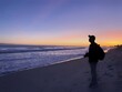 © RedBridge - Silhouette of a person on the beach. Scenic view of sunset in purple background along the beach, North Myrtle Beach, South Carolina