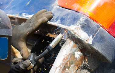 Worker in helmet repair detail in car service