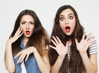 Two young girl friends having fun. Both making surprised faces.