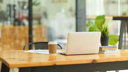 Image of Laptop computer stand on wooden table in coffee shop co-working space