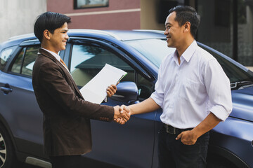 Seller and customer who bought a car shaking hands