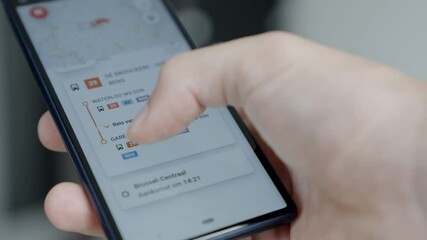 Scrolling through the smart mobility app on a black cell phone, planning public transport, illustrative editorial